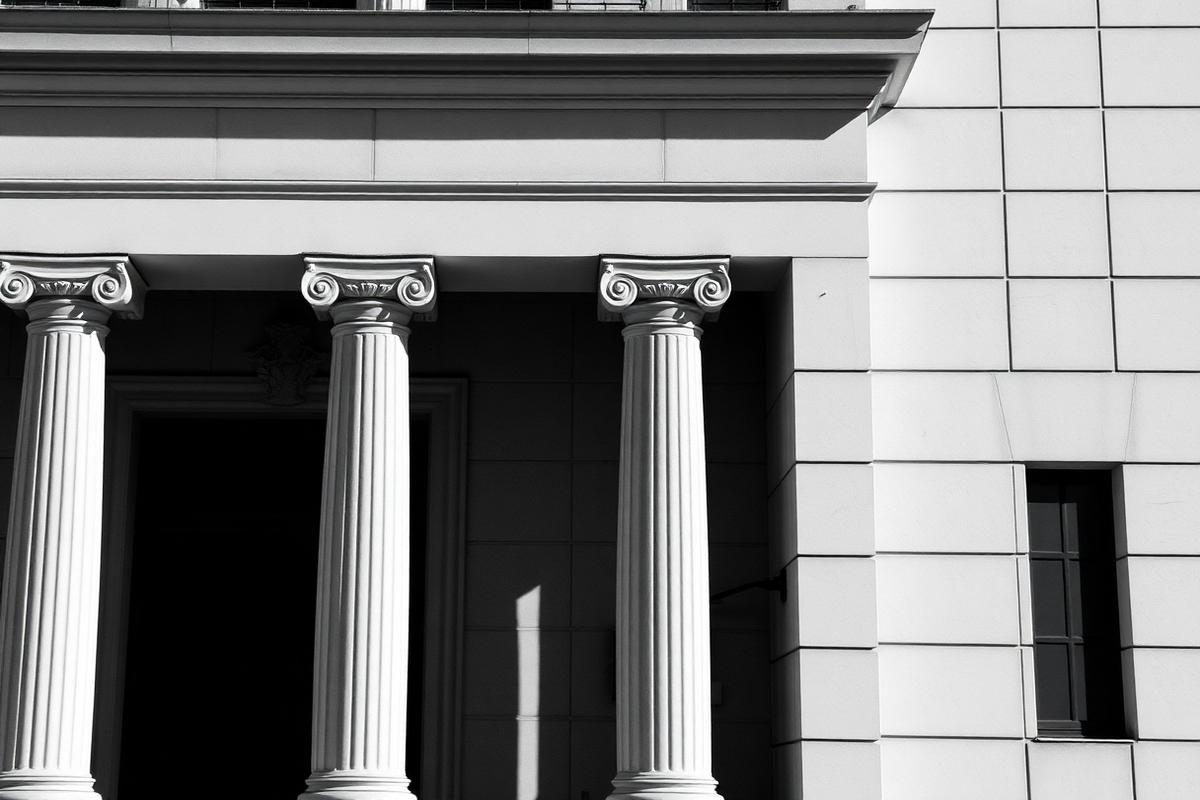 The columned facade of a classical institutional building in strong daylight